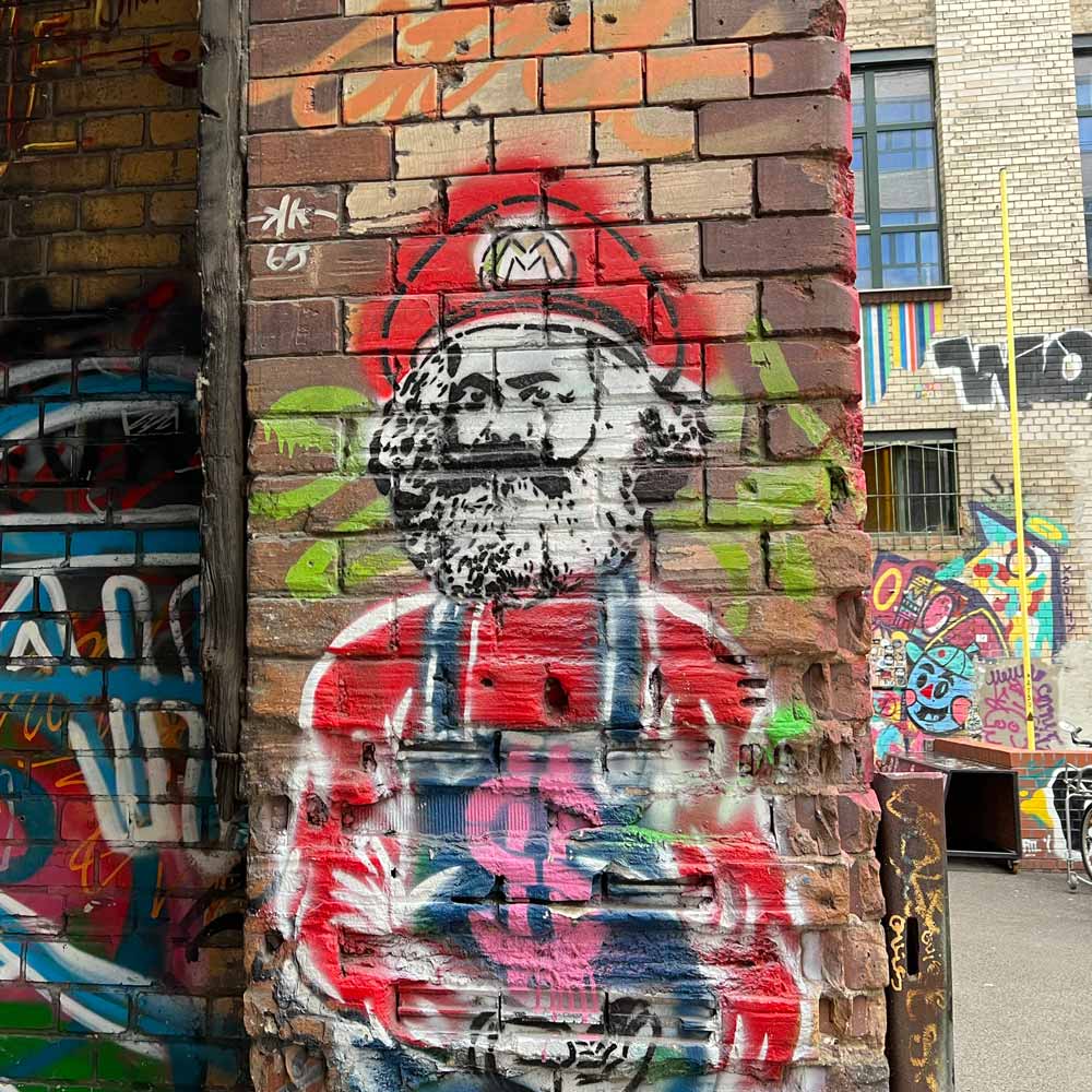 Graffiti von Karl Marx verkleidet als Super Mario als Symbolbild für den insanely great Newsletter "SaSa schreibt" von Sabine Samonig.